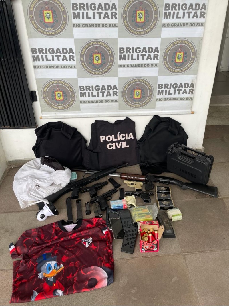 Foto mostra material apreendido pela BM, incluindo armas, drogas, munição, roupas, coletes balísticos.