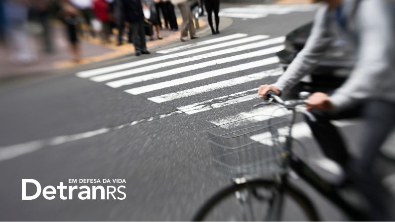 A foto mostra uma bicicleta passando por uma faixa de pedestre