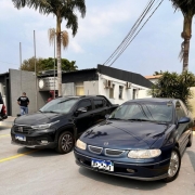 A foto mostra dois carros em frente a delegacia de polícia