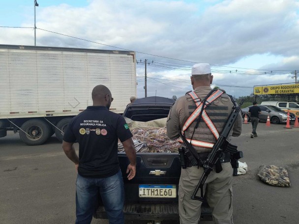 A foto mostra agentes de segurança e um carro com o material apreendido