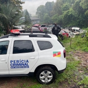 A foto mostra uma viatura do IGP e um desmanche de carros ao fundo