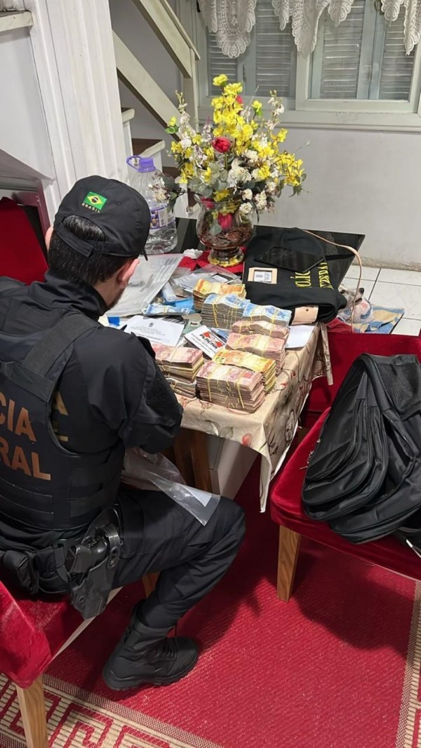 A foto mostra um policial apreendendo dinheiro