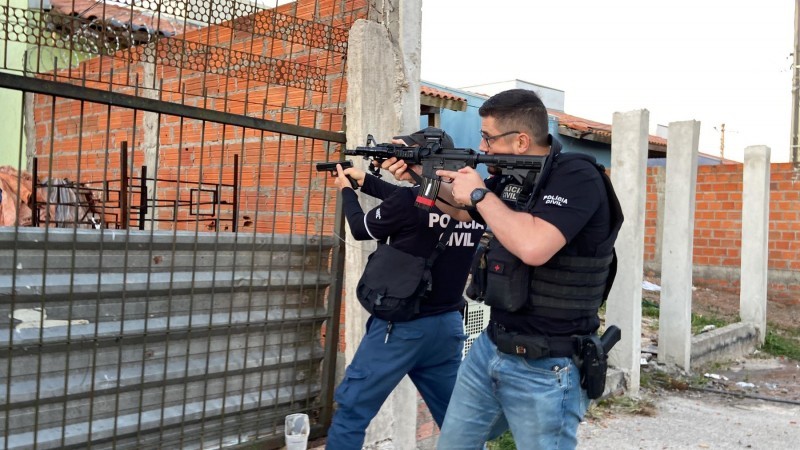 A foto mostra policiais armados em frente a uma residência