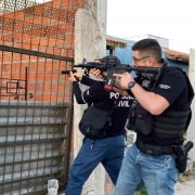 A foto mostra policiais armados em frente a uma residência