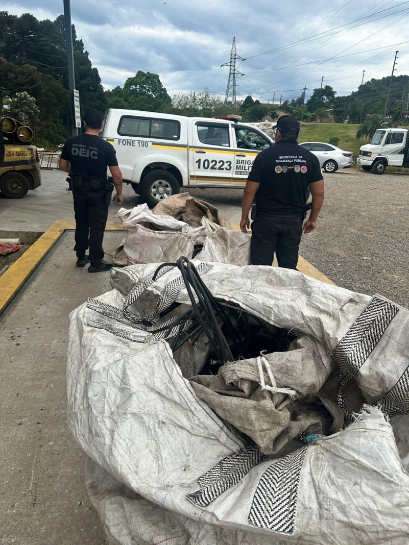 A foto mostra agentes de segurança pública e dois bolsões de fios