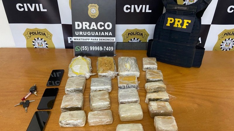 Porções de drogas, celulares e chaves de carros sob uma mesa, em posse da PC e PRF