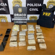 Porções de drogas, celulares e chaves de carros sob uma mesa, em posse da PC e PRF