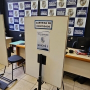 Foto do novo posto, com logotipos do IGP ao fundo. Na foto há duas mesas de atendimento com cadeiras e, atrás destas, divisórias nas quais leem-se "Carteira de Identidade" e o número do guichê.