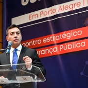 Secretário Caron fala no púlpito do evento. Ao fundo, lê-se "Encontro estratégico de Segurança Pública".