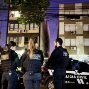 Quatro agentes de segurança em cumprimento de mandado e carro da Polícia Civil no amanhecer