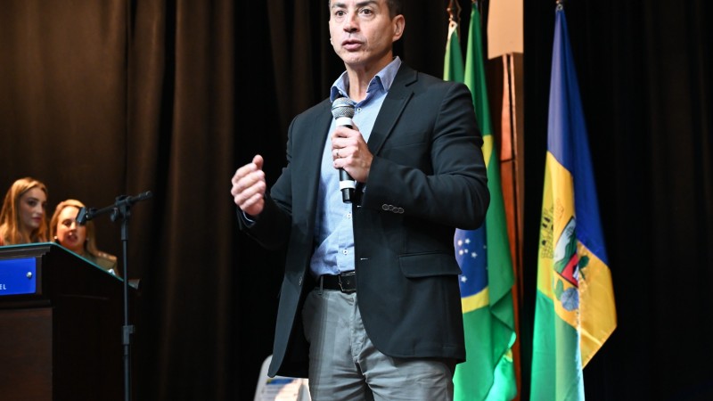 Sandro Caron na abertura do 3º Congresso Internacional de PJM, no palco. Atrás, bandeiras perfiladas.