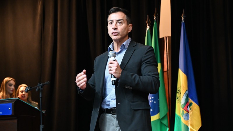 Sandro Caron na abertura do 3º Congresso Internacional de PJM, no palco. Atrás, bandeiras perfiladas.