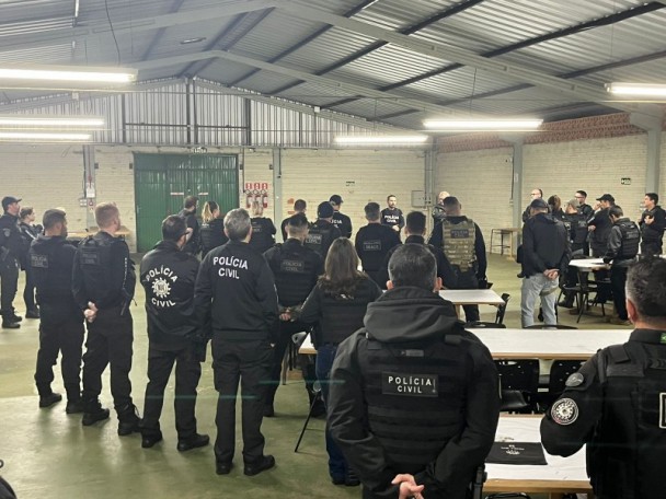 Cerca de 30 agentes da Polícia Civil uniformizados, de costas, assistem à instrução para a operação deflagrada em Passo Fundo