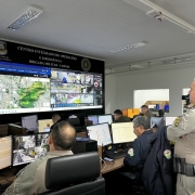 A imagem mostra policiais e agentes de segurança observando mapas e câmeras de monitoramento no Centro Integrado de Operações e Emergência