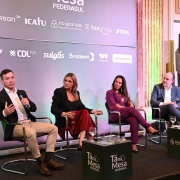 No palco do evento, quatro pessoas estão sentadas. À esquerda, o secretário de Segurança Pública Sandro Caron fala, gesticulando com o microfone na mão. Ao seu lado, da esquerda para a direita: a procuradora do MPRS Alessandra da Cunha, a diretora do Departamento Estadual de Proteção aos Grupos Vulneráveis da Polícia Civil, delegada Tatiana Bastos, e o presidente da Federasul, Rodrigo Sousa Costa.