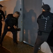 Três agentes fardados da Polícia Civil se preparam para arrombar uma porta de metal na operação Cifra Oculta