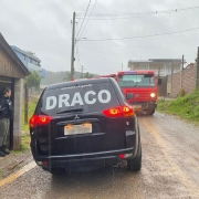Uma viatura da Draco trafega em uma rua de chão batido. No sentido contrário, um caminhão guincho se aproxima.