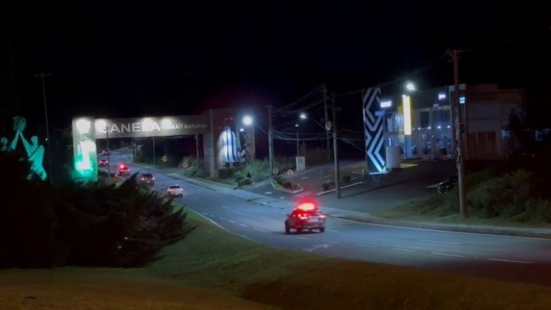 A imagem mostra viaturas da Polícia Civil cruzando o pórtico de entrada da cidade de Canela
