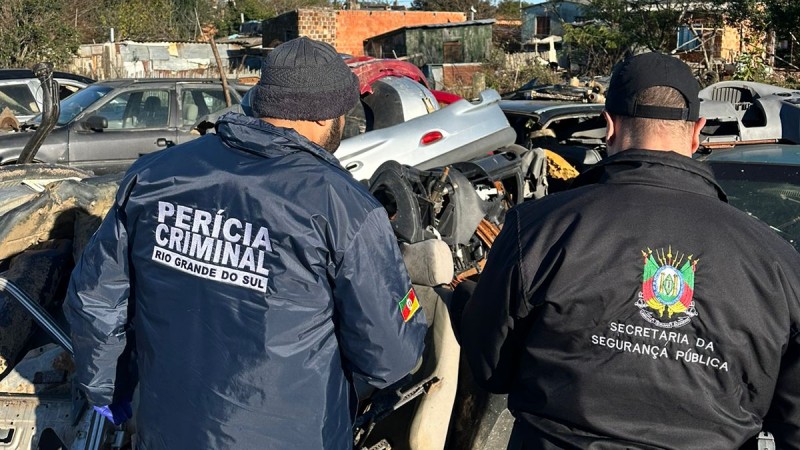 A imagem mostra um agente do IGP e um agente da Secretaria da Segurança Pública vistoriando um dos desmanches fiscalizados durante a operação