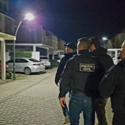 Quatro policiais, três homens e uma mulher, se dirigem ao local da apreensão, um condomínio de casas.