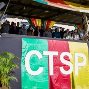 A imagem mostra as autoridades na tribuna principal durante a solenidade de formatura. Há uma grande bandeira com as cores do Rio Grande do Sul, estampada com a sigla CTSP, com as letras na cor branca