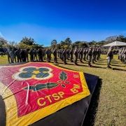 A imagem mostra um banner com o logotipo do CTSP em primeiro plano. Ao fundo, estão os formandos, em posição de descanso, durante a solenidade