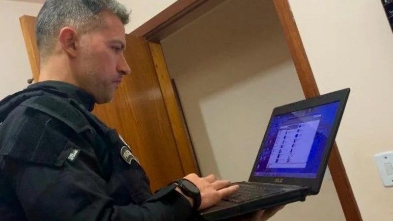 Homem fardado segura o computador notebook e analisa documentos