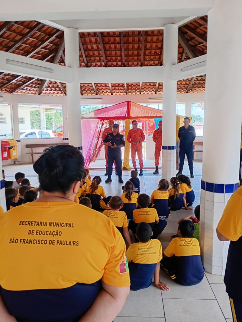 Na imagem, bombeiros passam informações às crianças