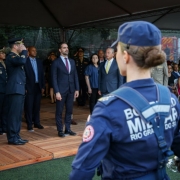 Foto mostra o governador Eduardo Leite no centro da foto. Militares fazem contin&ecirc;ncia para ele. Em primeiro plano, de costas para a c&acirc;mera, uma bombeiro militar fardada, tamb&eacute;m est&aacute; direcionada para ele.