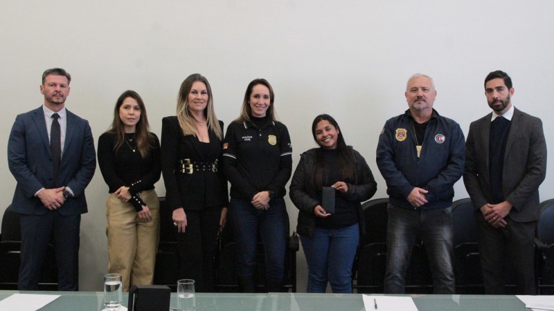A imagem mostra servidores das SSP-RS e da SSP-SP entregando aparelho de telefone recuperado