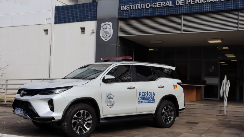 Uma fotografia colorida em plano m&eacute;dio e perspectiva em tr&ecirc;s quartos capta uma viatura oficial de Per&iacute;cia Criminal estacionada em frente &agrave; sede do Instituto-Geral de Per&iacute;cias do Rio Grande do Sul 